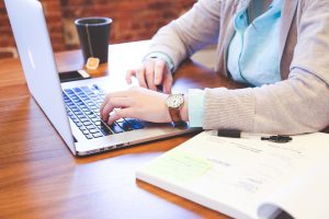 A person sitting at a desk and using a laptop.