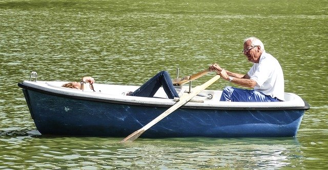 An elderly couple in a boat on a lake.