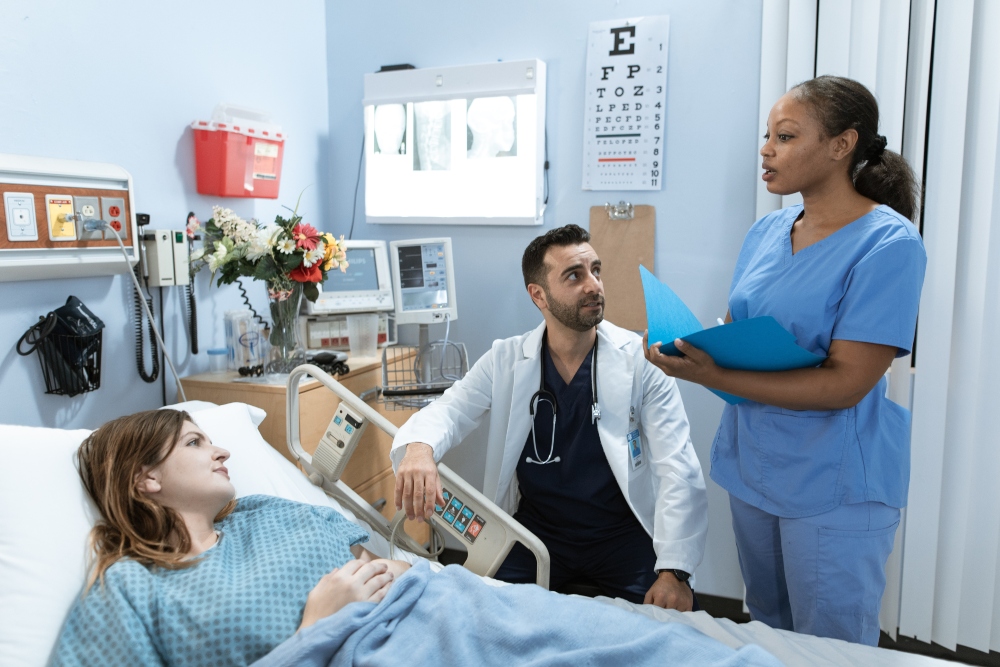 a patient lies in bed while the doctor and the nurse talk to her